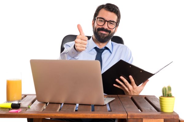 Businessman in his office with thumb up